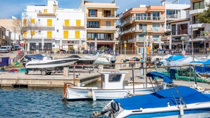 A marina with boats docked, a building with balconies, and a clear sky. - Holiday Apartment 'Es Port' close to the Beach with Sea View, Terrace & Wi-Fi (Cala Rajada)