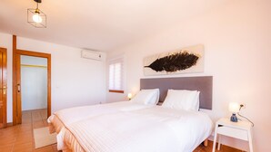 A bedroom with a large bed, a bedside table with a lamp, a wall-mounted artwork, and a door leading to another room. - Holiday Apartment 'Es Port' close to the Beach with Sea View, Terrace & Wi-Fi (Cala Rajada)