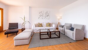 A living room with a sofa, ottoman, coffee table, and a lamp. - Holiday Apartment 'Es Port' close to the Beach with Sea View, Terrace & Wi-Fi (Cala Rajada)