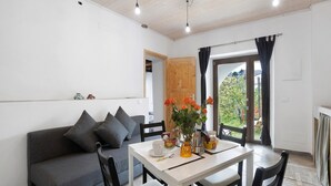 Ein modernes Wohnzimmer mit Sofa, Esstisch, Stühlen und Blick durch eine Tür.