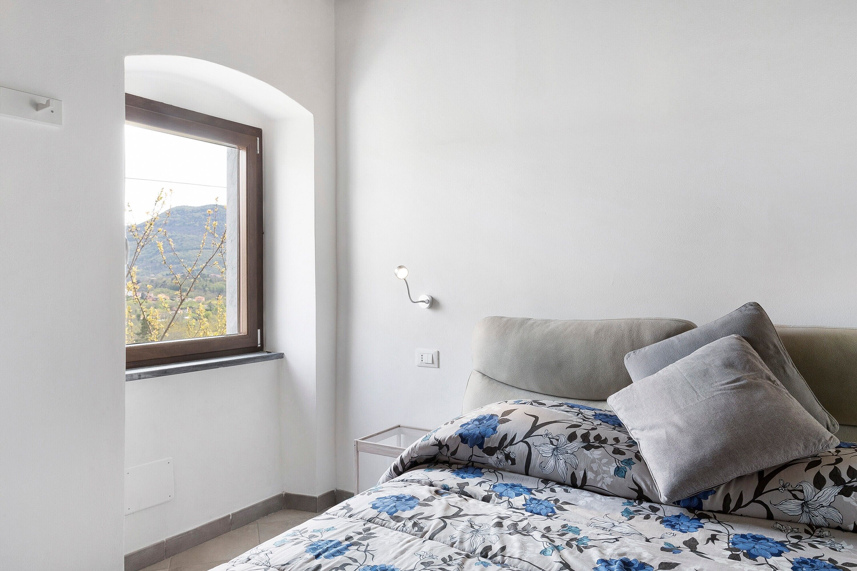 Una camera da letto con un letto, una finestra vista montagne e un comodino.