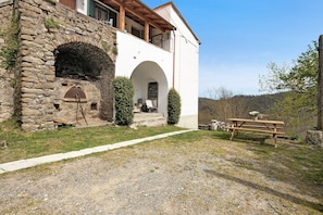A stone building with a stone oven, a wooden bench, and a picnic table.