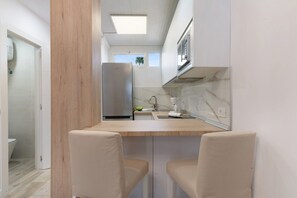 A compact kitchen with a built-in refrigerator, a small sink, and a window.