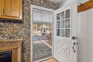 A kitchen with a stone wall, wooden cabinets, and a door leading to a patio with outdoor furniture.