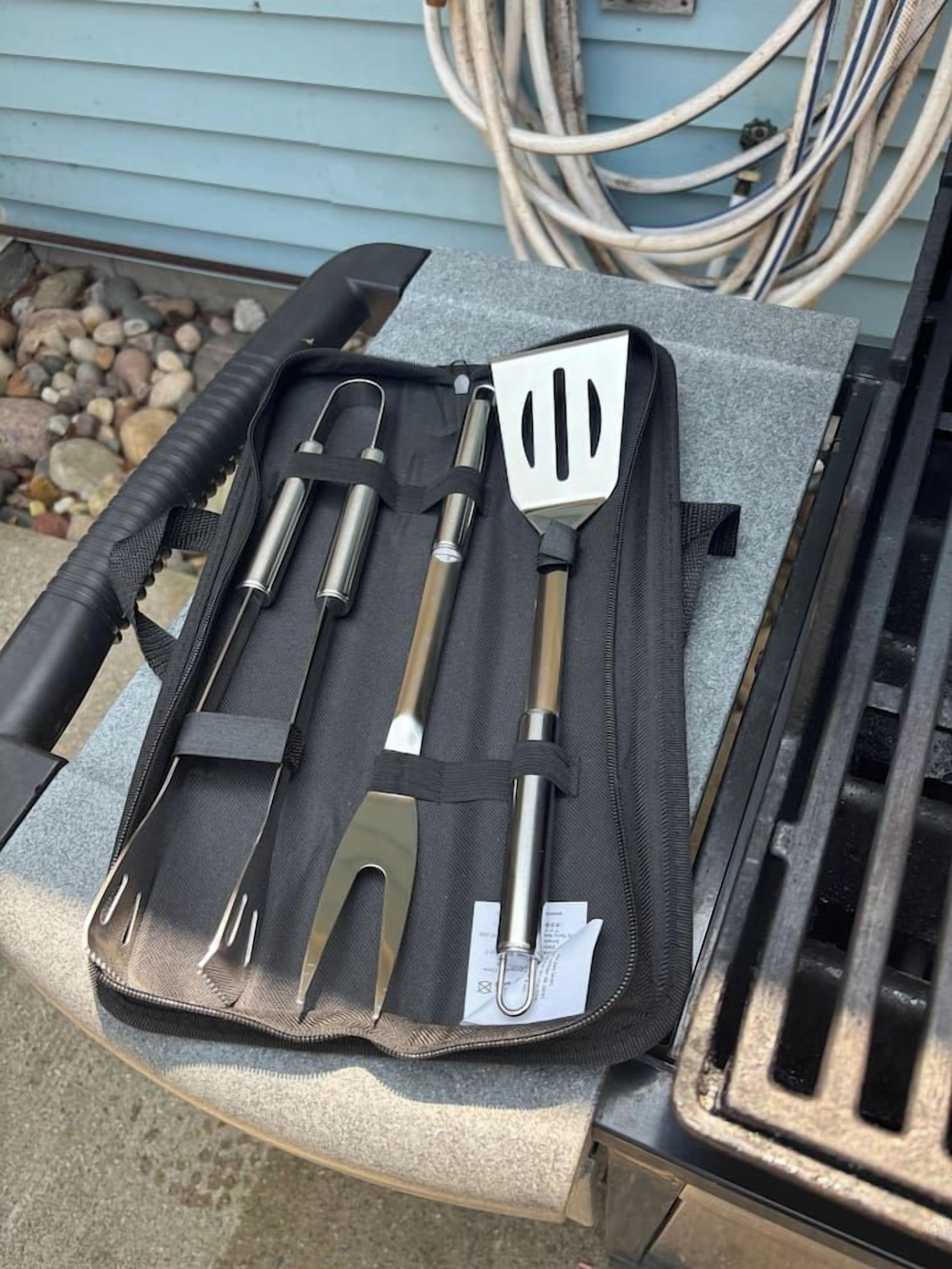 Un ensemble d’ustensiles de cuisine rangés dans une boîte noire, posé sur une table.