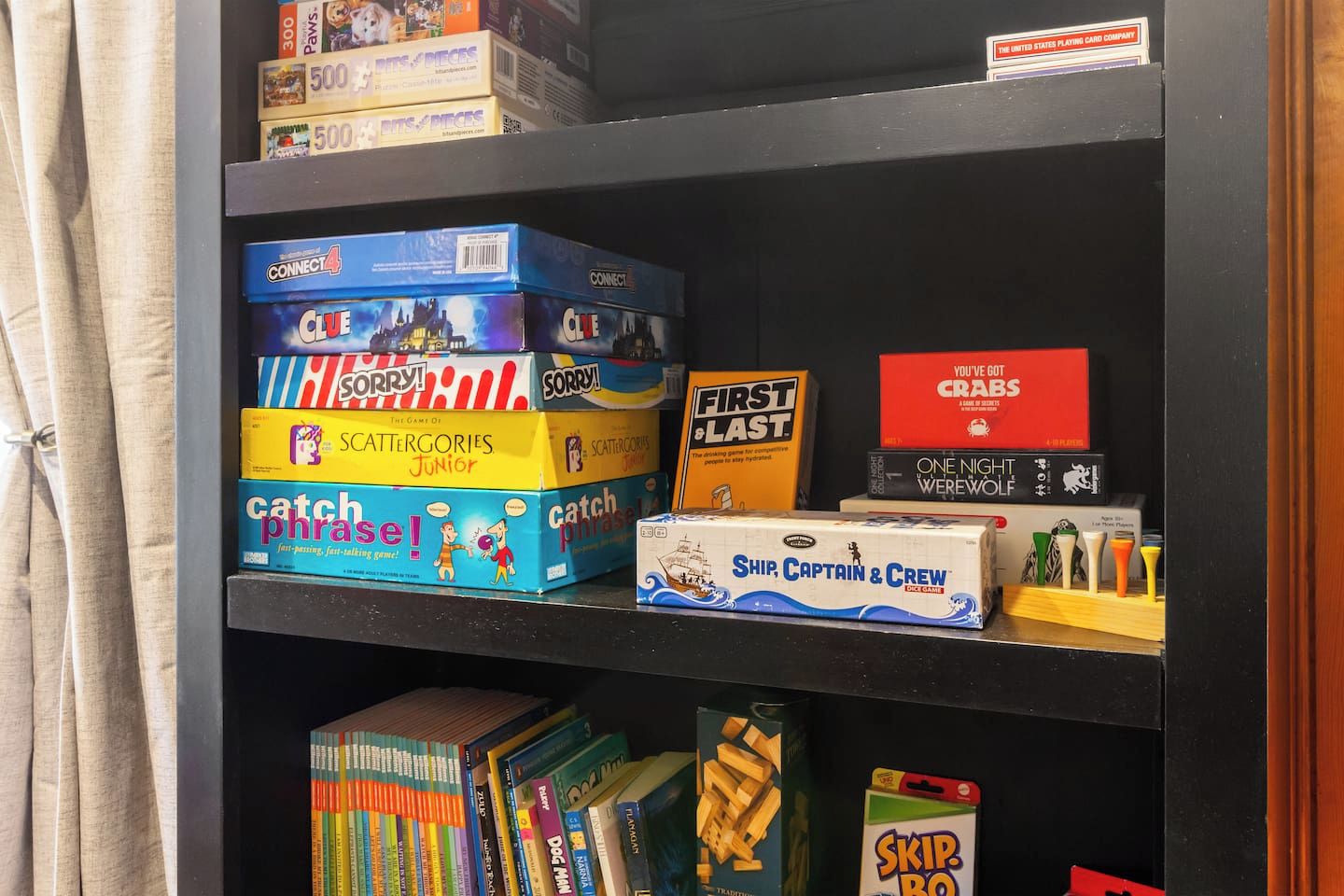 Une bibliothèque contenant divers jeux de société et livres.