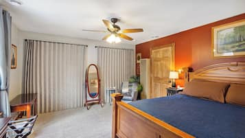 A hotel room with a bed, a desk, a chair, a ceiling fan, and a large mirror.