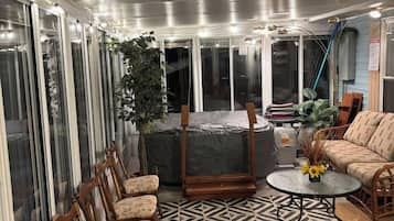 A covered patio area with a patterned floor, a seating arrangement, and a potted plant.
