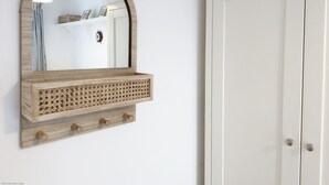 Un miroir mural avec un cadre en bois et une étagère décorative en bois située en dessous.