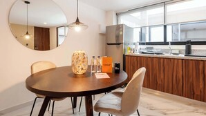 A modern kitchen with a large window, a round dining table with chairs, a hanging light fixture, and a refrigerator. - w* | Luminous 1BR with Amazing Deco in Polanco (Ciudad de México)