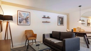 A modern living room with a sofa, armchairs, a coffee table, a TV mounted on the wall, a dining table with chairs, and a round mirror. - w* | Luminous 1BR with Amazing Deco in Polanco (Ciudad de México)