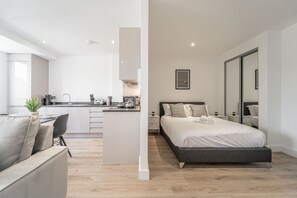 A modern apartment with a kitchenette, a dining area, and a bedroom with a large bed and a wardrobe. - Solihull Studio • WiFi • NEC • BHX (Solihull)