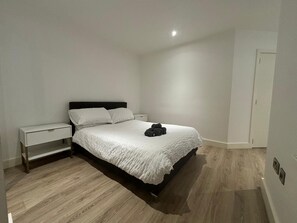 A bedroom with a bed, a nightstand, and a wooden floor. - Solihull Studio • WiFi • NEC • BHX (Solihull)
