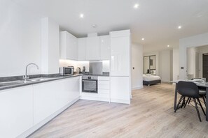 A modern kitchen with white cabinetry, a built-in oven, and a microwave. - Solihull Studio • WiFi • NEC • BHX (Solihull)