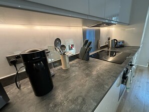 Une cuisine moderne équipée d’une machine Nespresso, d’une bouilloire, d’un grille-pain et d’un bloc à couteaux.