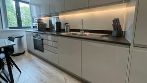 Een moderne keuken met een groot eiland, inbouwapparatuur en een raam dat voor natuurlijk licht zorgt.