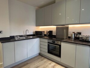 Een moderne keuken met een magnetron, broodrooster, waterkoker en oven.