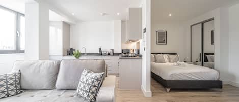 A modern apartment with a living area, kitchenette, and a bedroom.