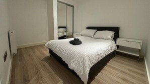 Een slaapkamer met een groot bed, een nachtkastje, een spiegel en een kledingkast.