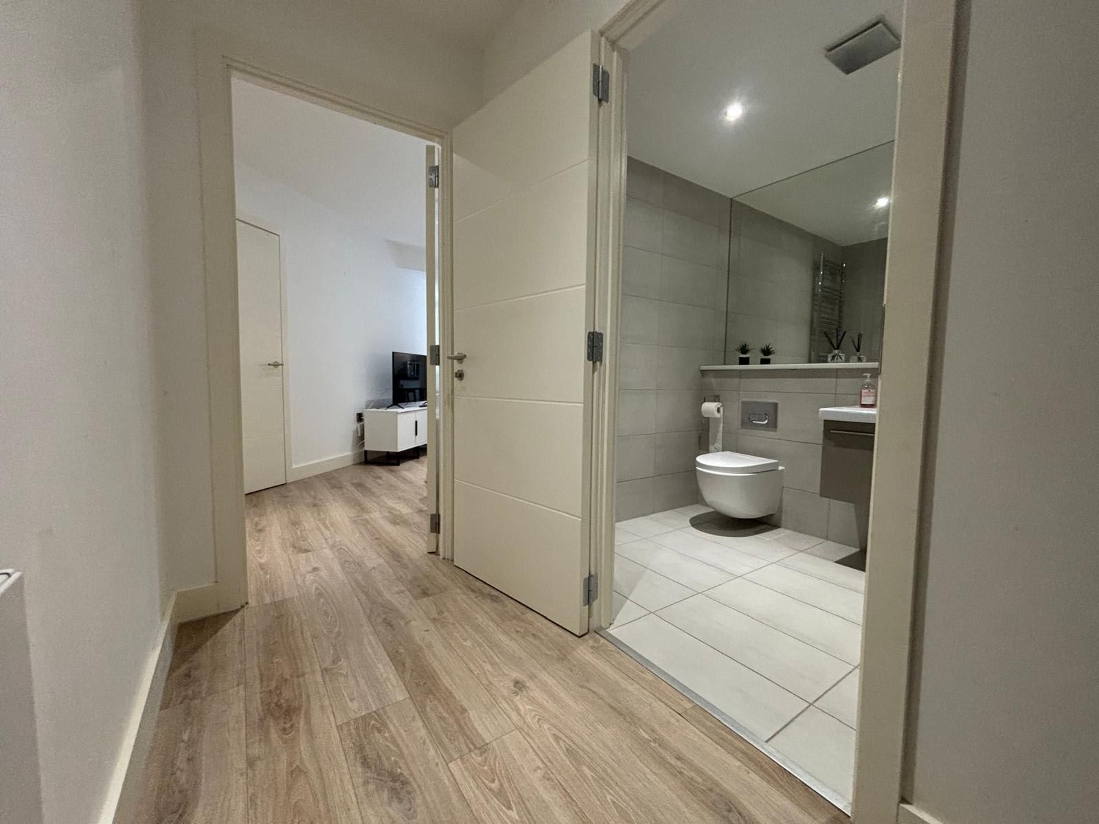 A modern bathroom with a toilet, sink, and mirror.