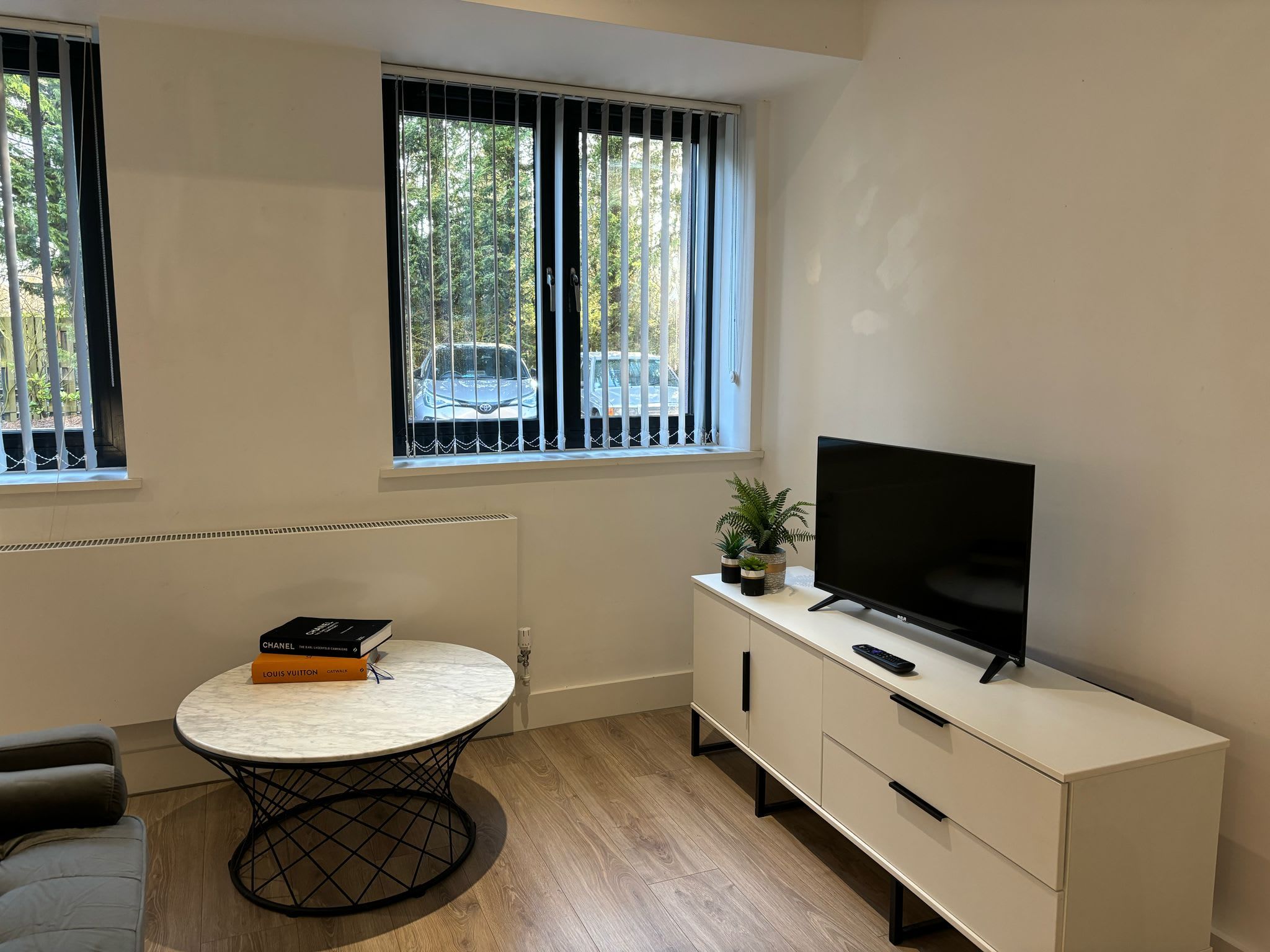 A modern room with a round table, a flat-screen TV, and a white cabinet.
