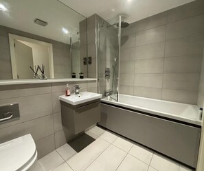 Une salle de bain moderne avec une douche à l’italienne, un lavabo blanc et une grande baignoire.