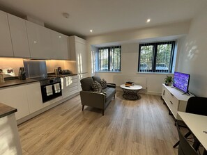 A modern kitchen with white cabinets, a dining area with a round table, and a seating area with a sofa. - Solihull Studio • WiFi • NEC • BHX (Solihull)