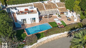 Ein modernes Haus mit Schwimmbad, Außenbereich zum Sitzen und einem gepflegten Garten.