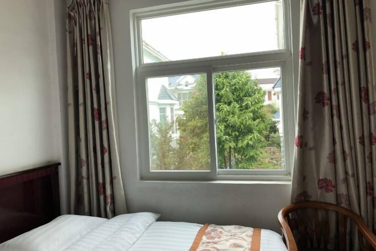 A bedroom with a bed, a window, and curtains.