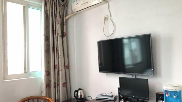Une chambre dotée d’un bureau en bois, d’un téléviseur à écran plat, d’un ordinateur de bureau, d’une bouilloire et d’une machine à café.