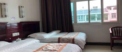 Habitación de hotel con dos camas, un aparador de madera, una silla y una ventana con vistas a edificios.