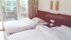 Une chambre d’hôtel avec deux lits, une fenêtre avec des rideaux et un luminaire fixé au mur.
