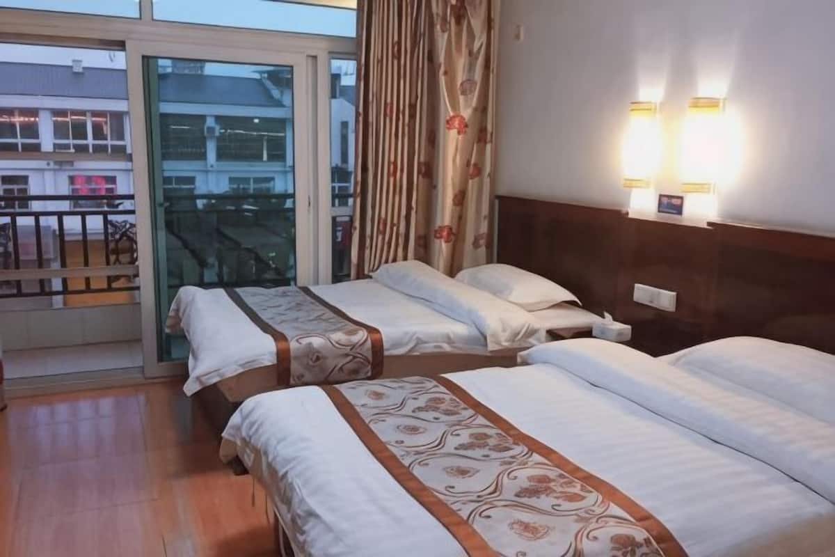 A hotel room with two beds, a balcony, and a view of the outside.