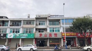 Un immeuble à plusieurs étages, doté de différents commerces en rez-de-chaussée, notamment un restaurant et un centre de services.