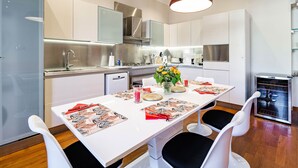 A modern kitchen with white cabinets, stainless steel appliances, and a dining area with a white table set for four. - Market Square - 2 bedrooms - 2 baths - private garage - large 90 sq meters (Beaulieu-sur-Mer)