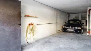 A garage with a black car parked inside, a broom, and a hose on the wall. - Market Square - 2 bedrooms - 2 baths - private garage - large 90 sq meters (Beaulieu-sur-Mer)