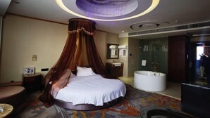 Une chambre d’hôtel moderne dotée d’un lit rond avec un baldaquin, d’une baignoire et d’un espace douche.