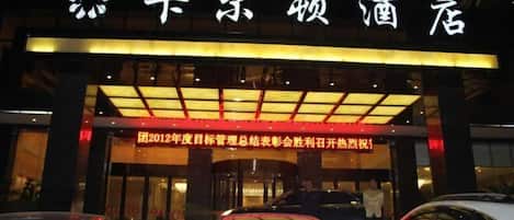 A hotel entrance with illuminated signage and a red awning.