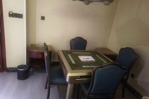 A small dining area with a table and four chairs. There is a trash can and a small cabinet with a red top.