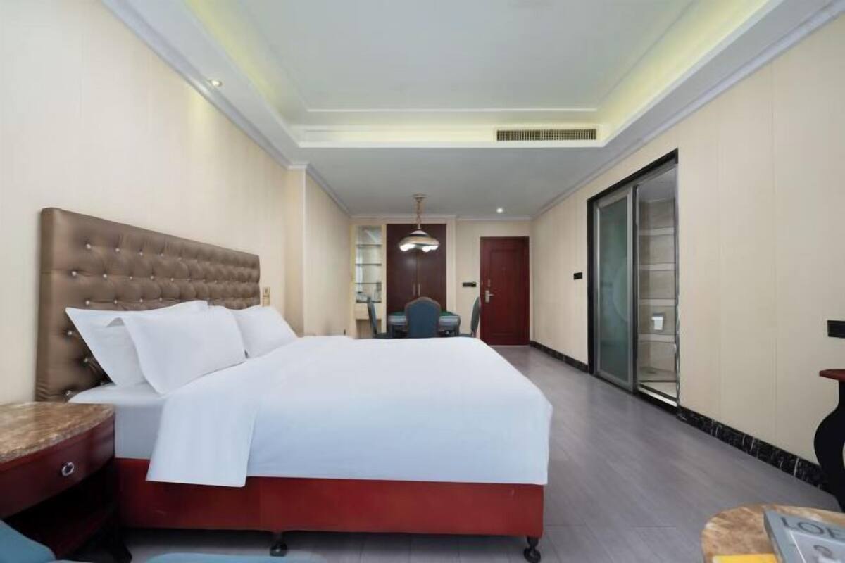 Habitación de hotel con una cama grande, un escritorio, una silla y una puerta corredera.