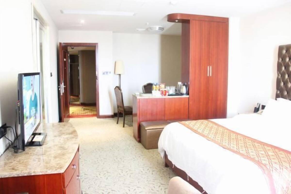 Una habitación de hotel con cama, escritorio, televisor de pantalla plana, armario y silla.