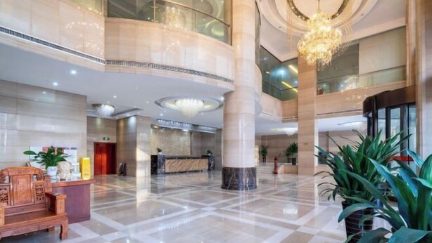 Un hall d’entrée spacieux, doté d’un comptoir de réception, d’un lustre et d’une grande colonne.