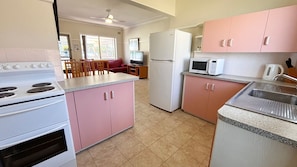 A compact kitchen with a stove, microwave, refrigerator, and a sink. - Clarkes Flat 1 - town centre unit (SOUTH WEST ROCKS)