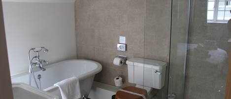 A modern bathroom with a freestanding bathtub, a toilet, and a glass-enclosed shower area.