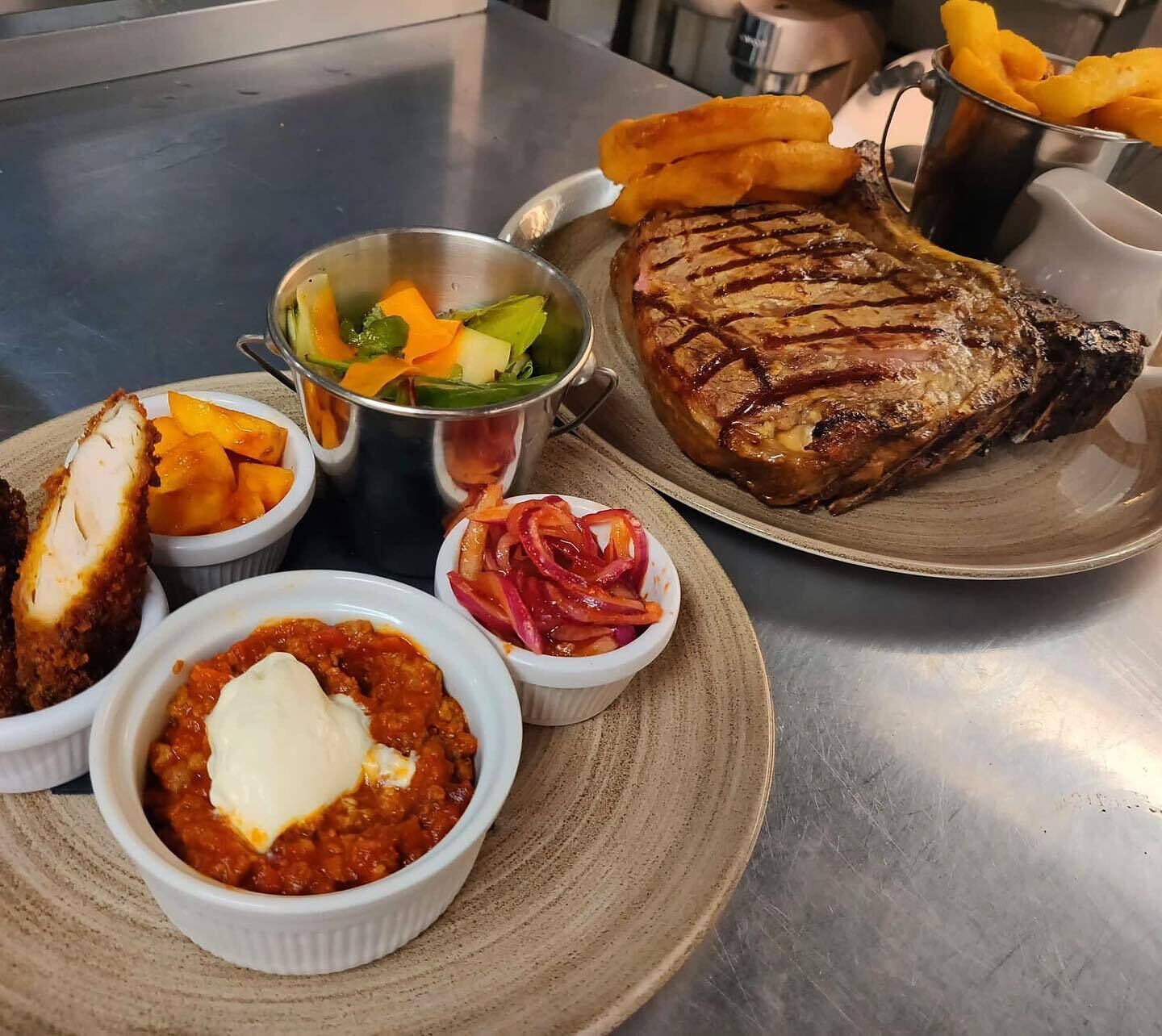 A plate with a grilled steak, side dishes, and a bowl of vegetables.