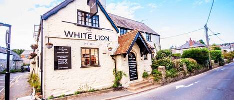 A traditional pub named "The White Lion" with a signboard advertising freehold family run pub, traditional beers & ales, and a large garden.