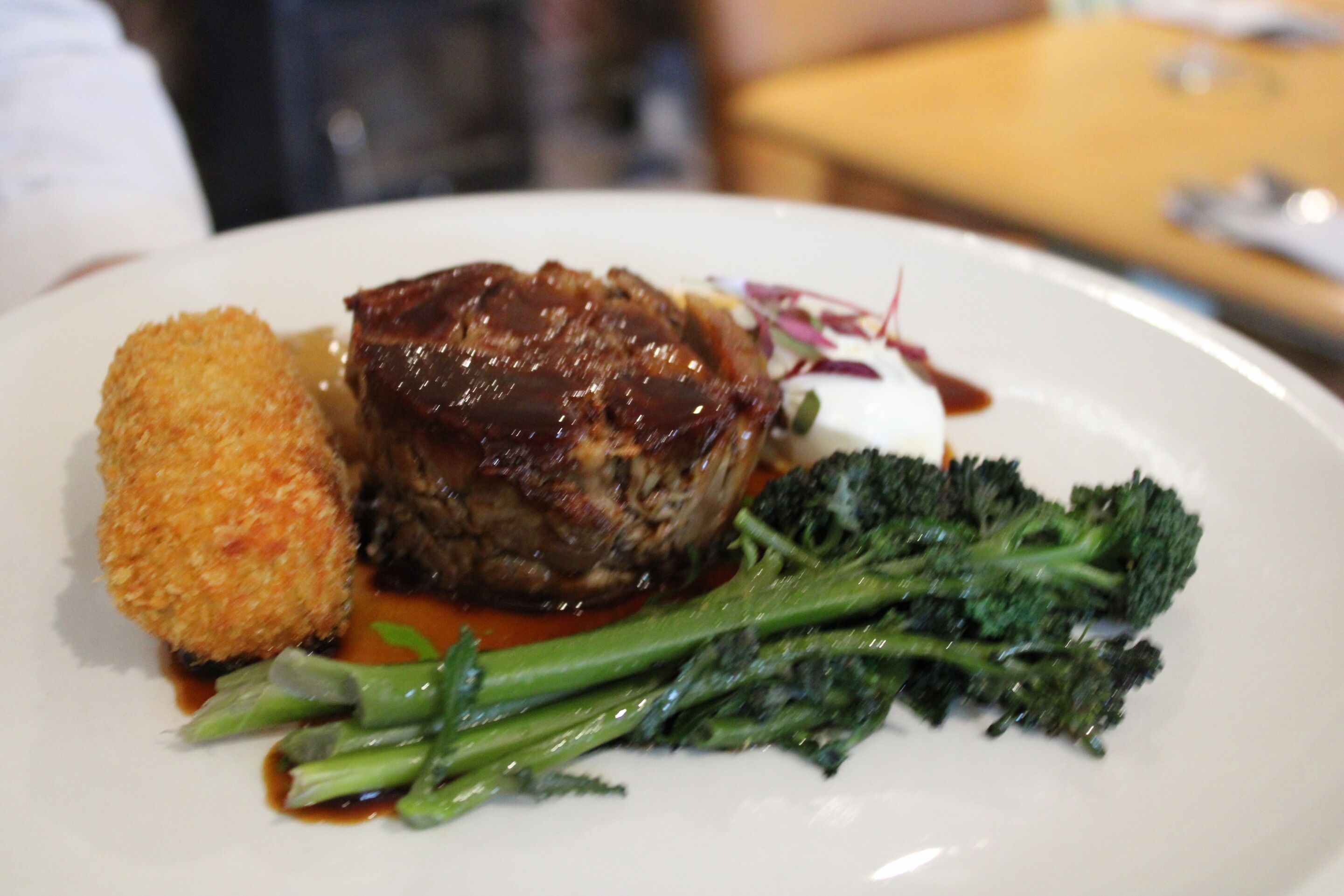 Un plato con un trozo de carne, algo empanizado y brócoli.