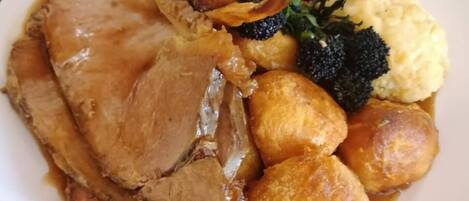 A plate of food with roast beef, Yorkshire pudding, mashed potatoes, and vegetables.