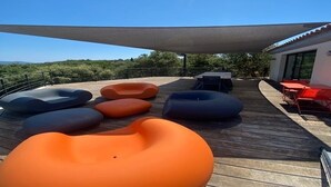 Une terrasse avec des sièges et une structure pour créer de l’ombre.