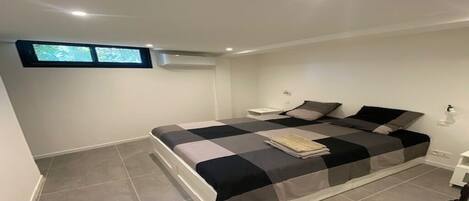 Une chambre à coucher avec un lit, une petite table de chevet, une commode et une fenêtre.